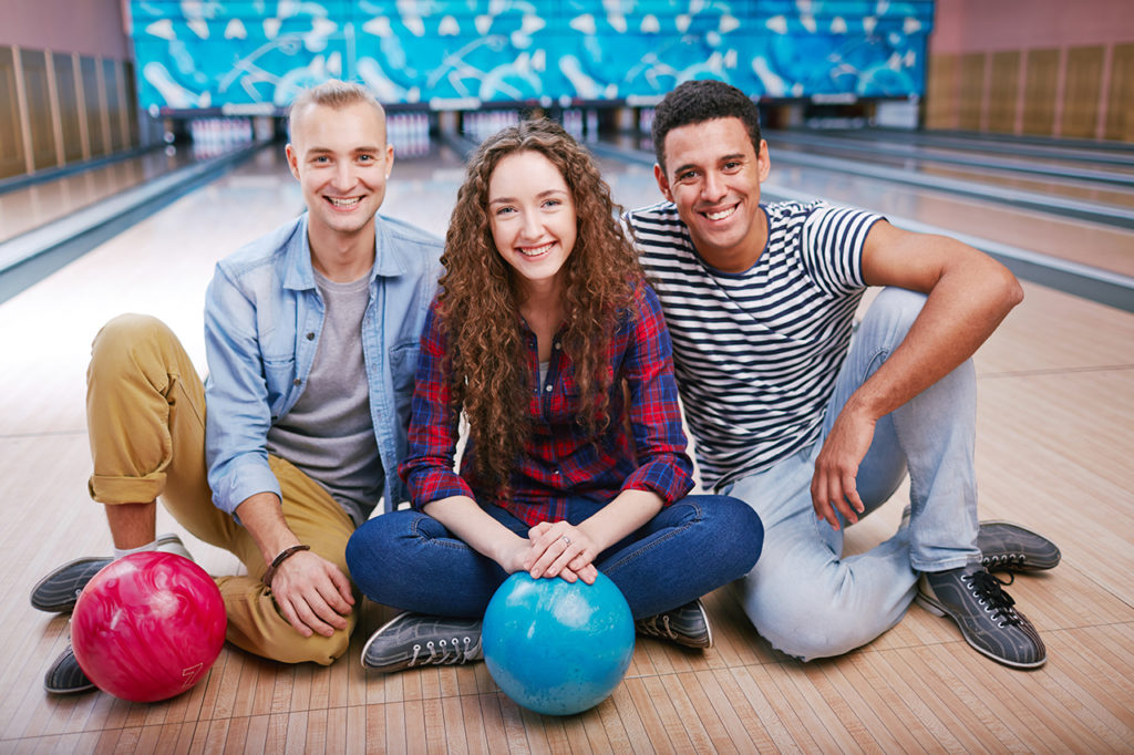 Three close friends sitting on floor in bolwing club